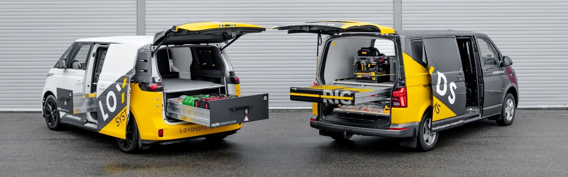 Två transportbilar parkerade mot en vägg med bilinredning från Loyds Systems